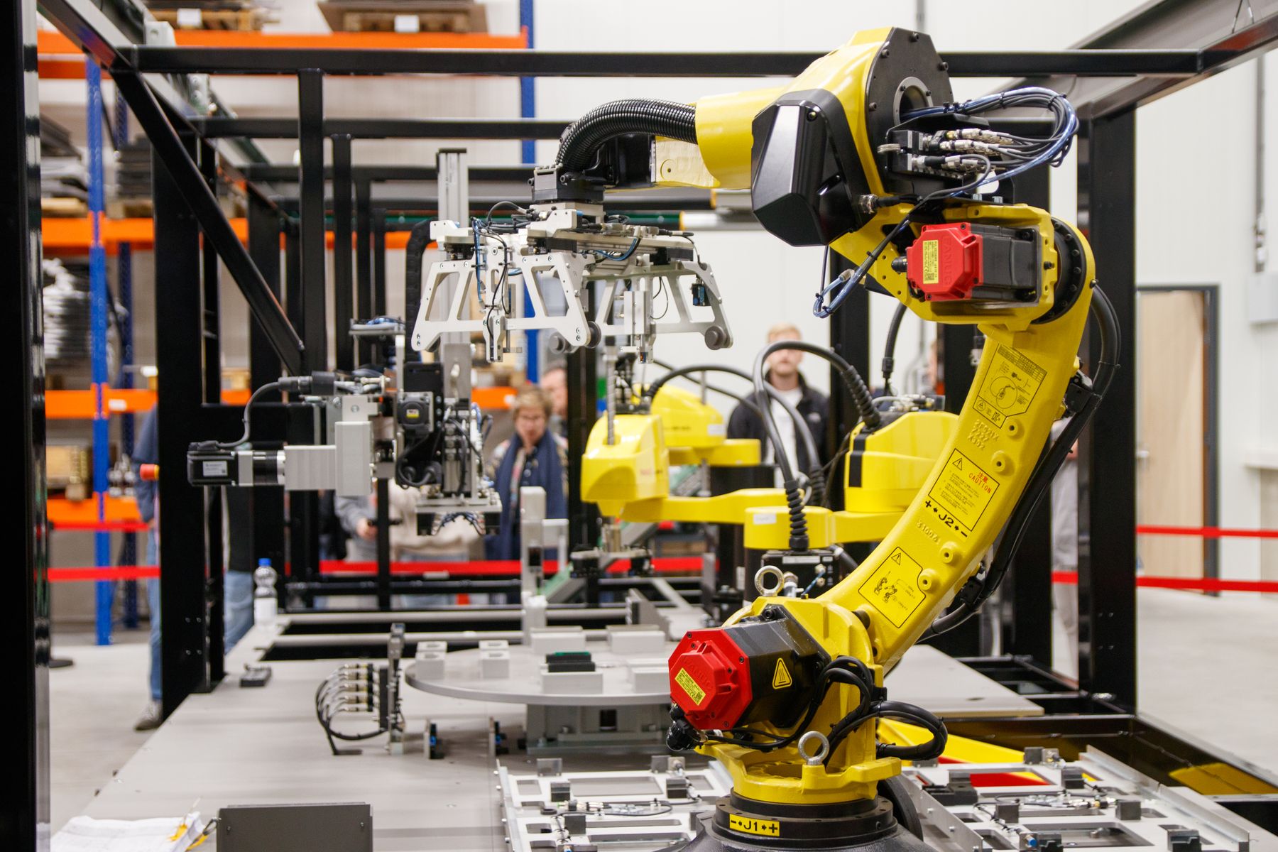 Yellow robot arm with a metal gripper beside fixtures inside a black frame.